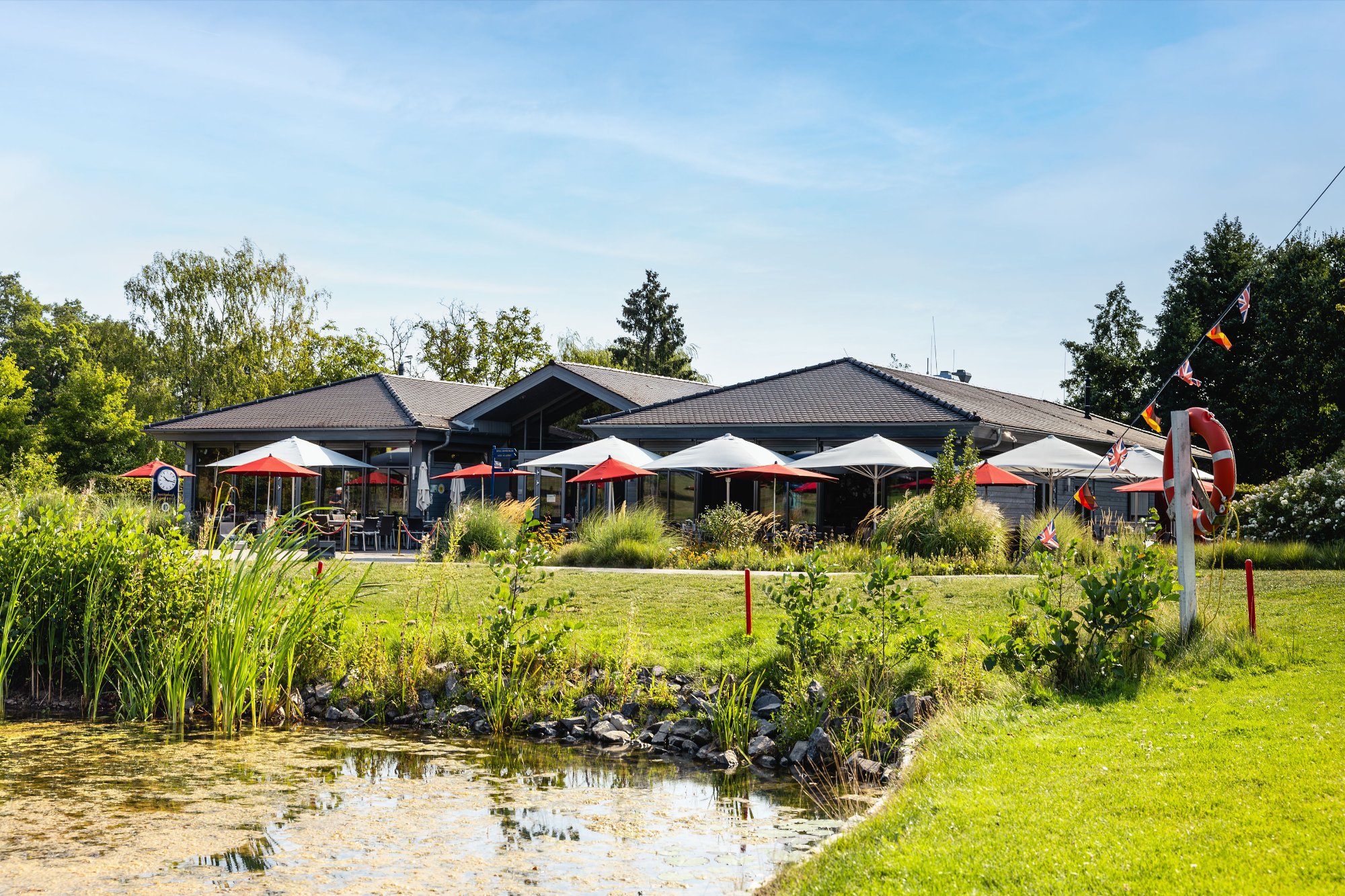 Das moderne Clubhaus am Royal Homburger Golf Club in Bad Homburg mit Sonnenterrasse und Teich